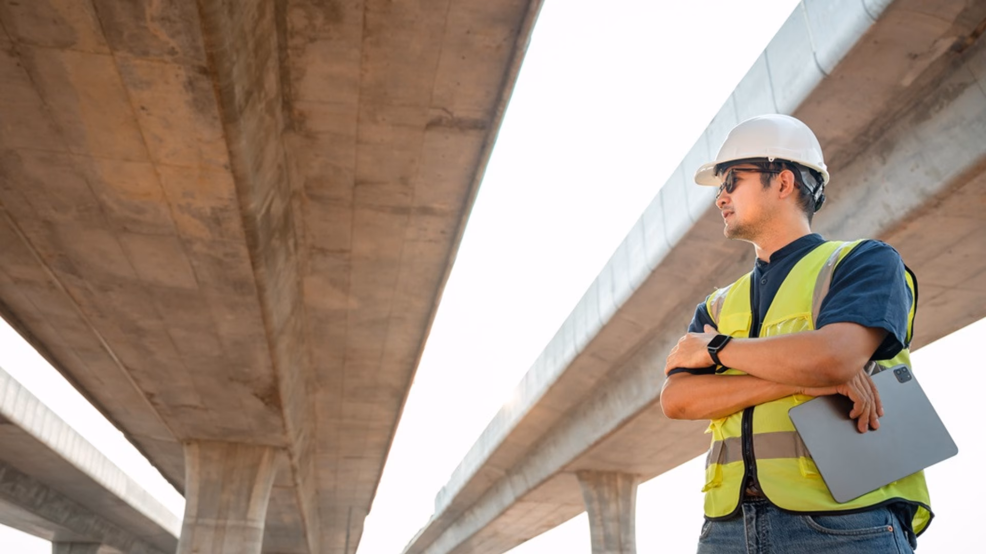 Aziatische mannelijke ingenieur die werkt bij het plannen van een bouwproject Ingenieur die toezicht houdt op de bouw van een betonnen brug op een bouwplaats