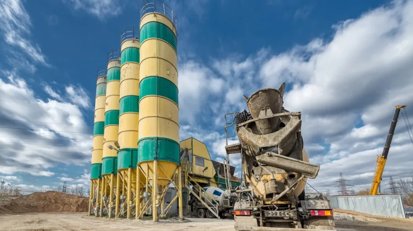 Betoncentrale Een betonnen vrachtwagenmachine wacht op laden nabij de cementopslagtorens. Zonnige dag blauwe lucht