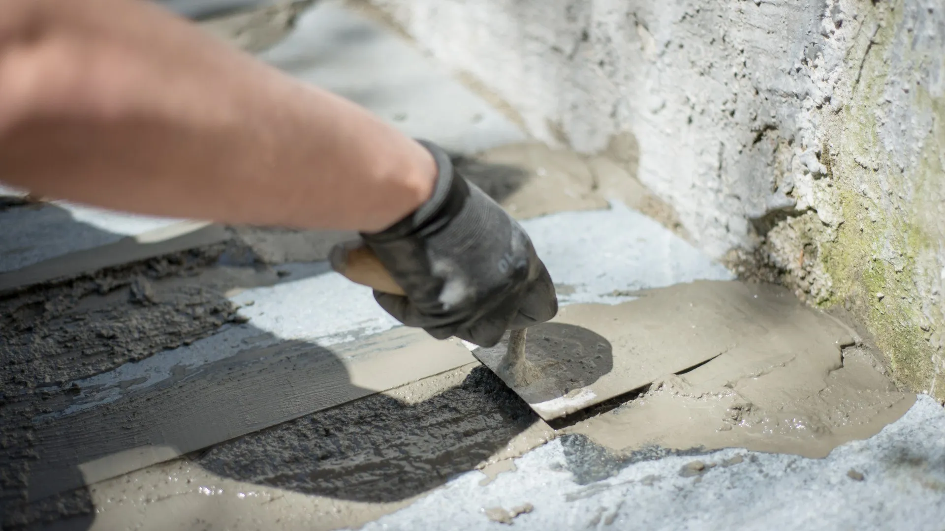 Medewerker voert een handmatige reparatie van beton uit met mortel en troffel