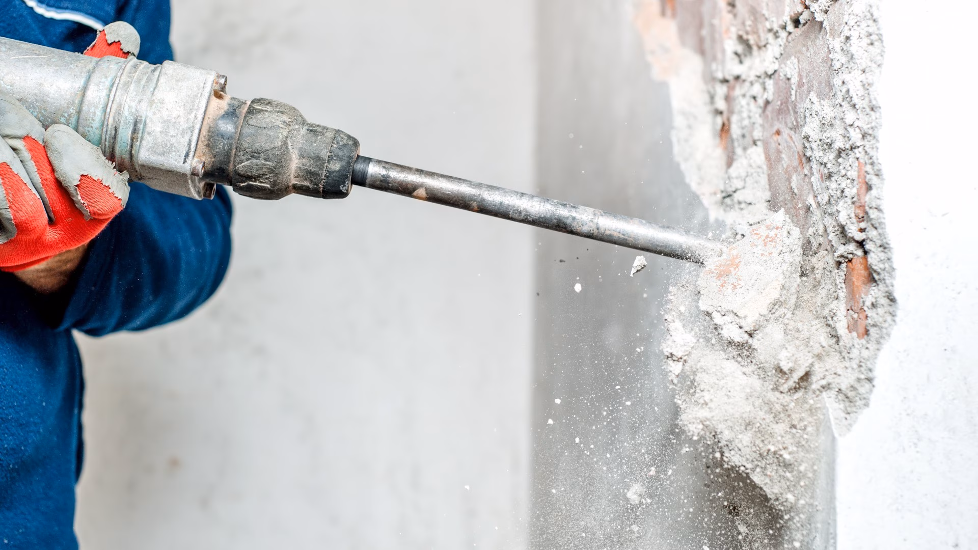Medewerker boort met een drilboor in een betonnen wand