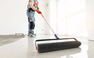 Medewerkers bewerkt een nieuwe betonnen dekvloer beton met een naaldrol