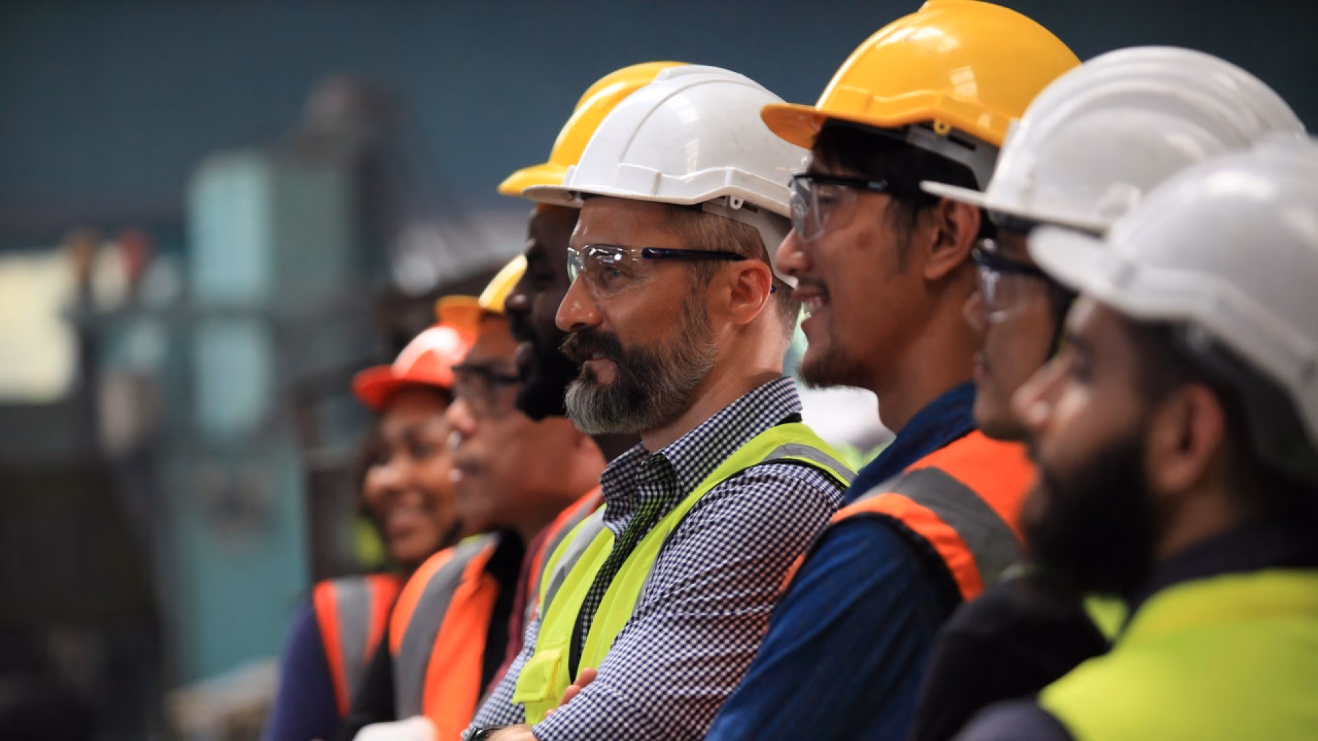 Een team van ingenieurs met helmen, veiligheidsbrillen en hesjes.