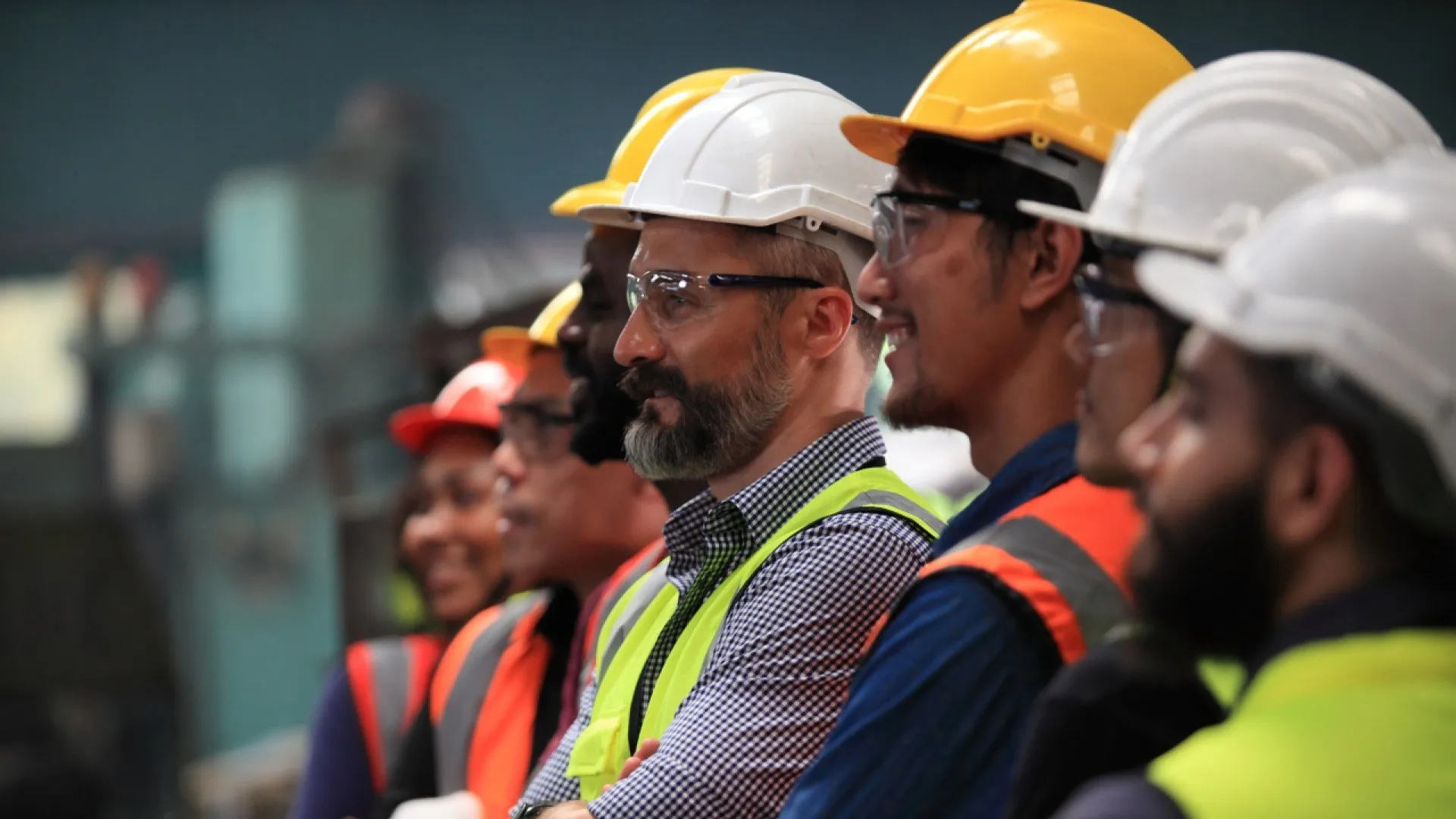 Een team van ingenieurs met helmen, veiligheidsbrillen en hesjes.