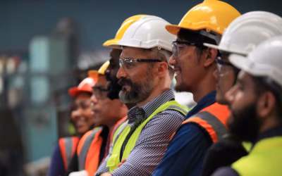 Een team van ingenieurs met helmen, veiligheidsbrillen en hesjes.