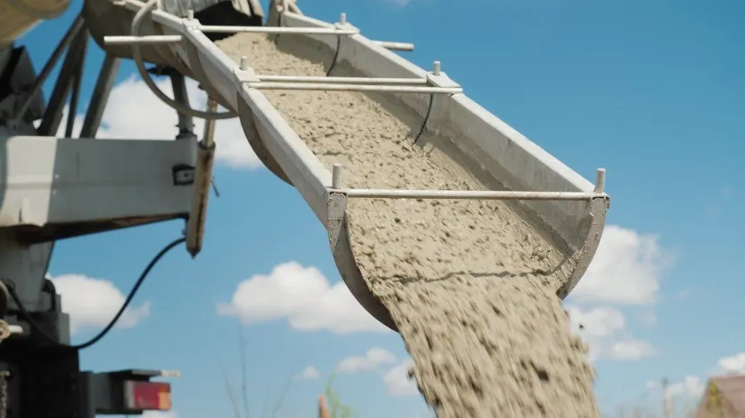 Een cementmixer lost betonspecie op een bouwplaats