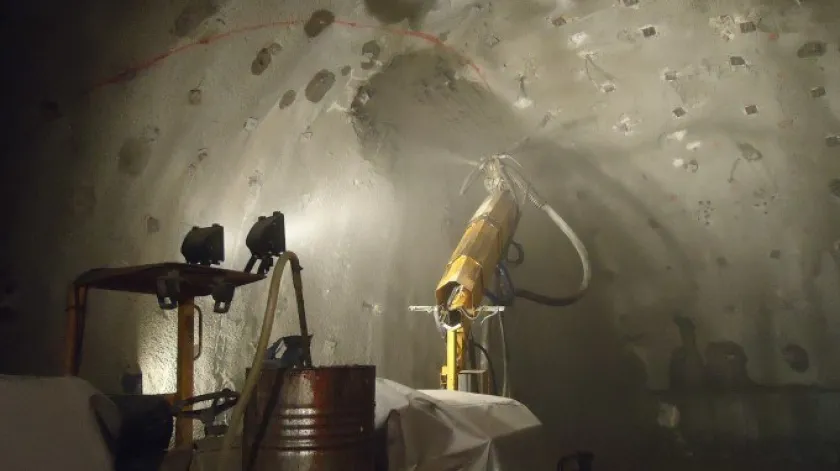 Een robot brengt spuitbeton aan in een tunnel.