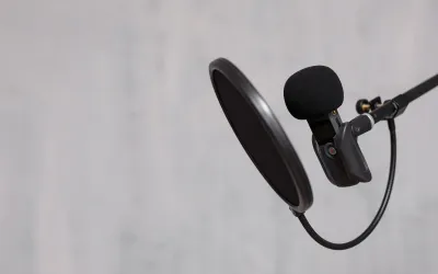 Microfoon met daarvoor een pop filter en een grijze achtergrond.
